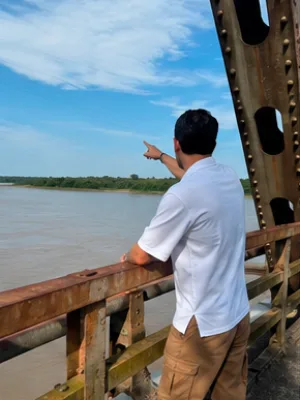 Alvarán señala hacia el río desde la estructura de un puente