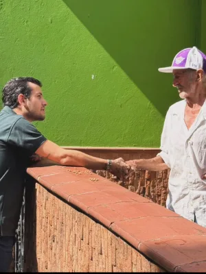 Alvarán estrecha la mano de un hombre mayor sobre el muro de una casa